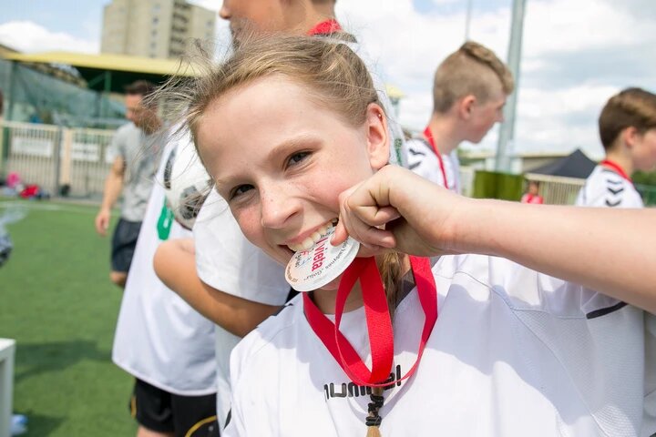 Mergaitė džiaugiasi futbolo medaliu